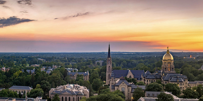 Aerial view of campus at sunset featuring the Basilica and Main Building