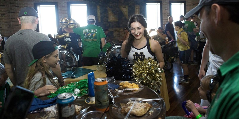 A cheerleader speaking with a family at a table with drinks