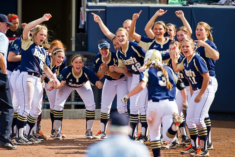 The Softball team celebrates as Emilee Koerner (3) heads for home plate after a home run.