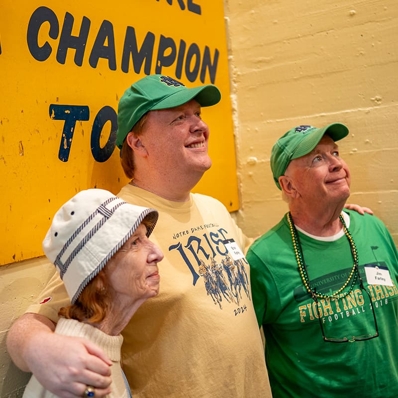 A family in Notre Dame's iconic football tunnel taking a photograph with the Play Like a Champion Today sign.